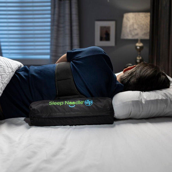 Person lying on a bed with a Sleep Needle Up product, in a bedroom setting.
